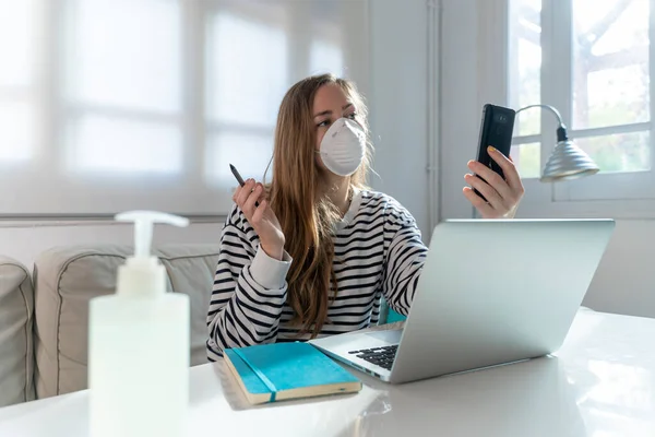 Coronavirus. Woman at home wearing protective mask. Woman in quarantine for coronavirus on the couch cleaning her hands with sanitizer gel. Working from home. Clean your hands with sanitizer gel.