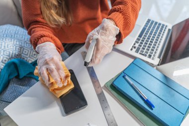 Coronavirus. Koronavirüs salgını sırasında evde dezenfektanla yüz maskesi ve lastik eldiven temizleyen bir kadın. Enfeksiyon önleme ve salgının kontrolü. Evini dezenfekte et..