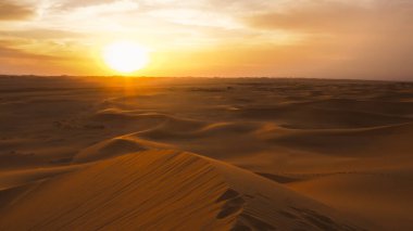 İnanılmaz çöl batımı. Sıcak renkleriyle güzel bir Arap çölü. Abu Dabi 'deki kum tepelerinin renkli hatları. 