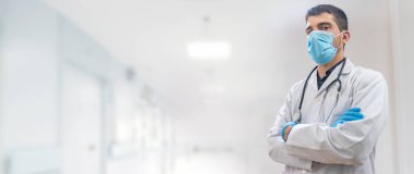 Coronavirus. Doktorlar hastanede çalışıyor ve koronavirüsle savaşıyorlar. Koruyucu kıyafetli ve maskeli bir erkek doktor hastalığın tedavisini arıyor. Metni kopyala Hastane geçmişi. Pankart.