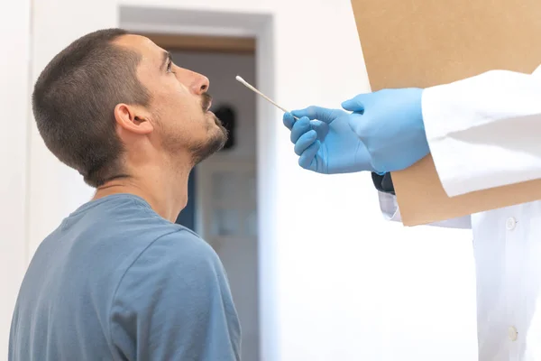 Coronavirus. Patient care. Diagnostics. Doctor visiting unhealthy man at home, coronavirus test. Doctor consults patient sitting at doctor office. Face mask and rubber gloves for prevention.