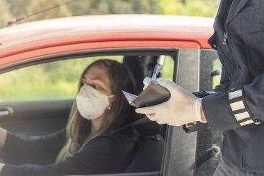 Coronavirus. Tam korumalı ekipmanlı bir polis teknisyeni arabasında oturan genç bir kadından örnek alıyor. Coronavirus mobil test ünitesi. İzole edilmiş. Karantina. 
