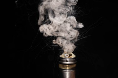 Elektronik sigara yakarak siyah arka planda duman yayıyor.