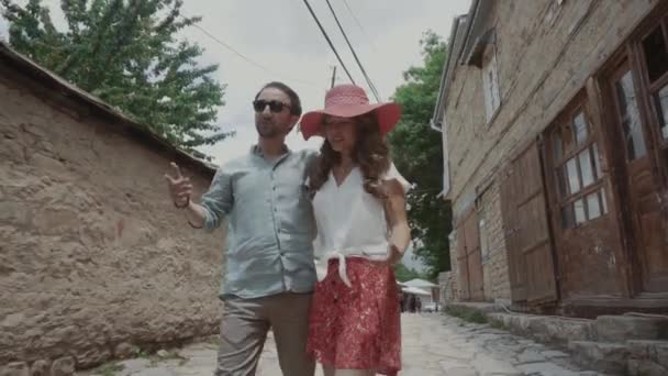 Пара влюбленных в повседневной одежде гуляет, держа за руки узкую улочку старого города — стоковое видео