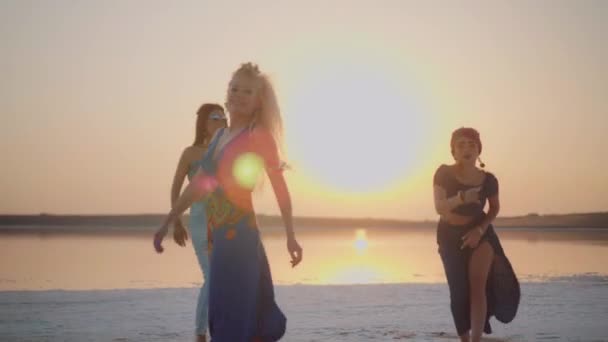 Unga dansande flickor vid sjön i solnedgången — Stockvideo