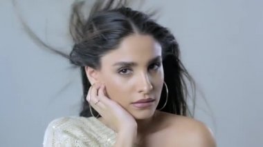 Uzun kıvırcık siyah saçlı güzel kadın. Moda modeli kameraya bakıyor.