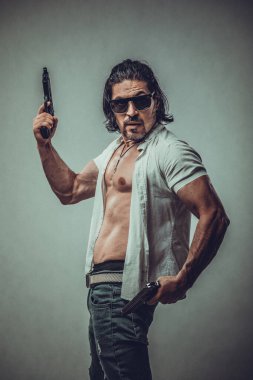 Elinde silah tutan genç bir adamın kaslı vücut modeli portresi.