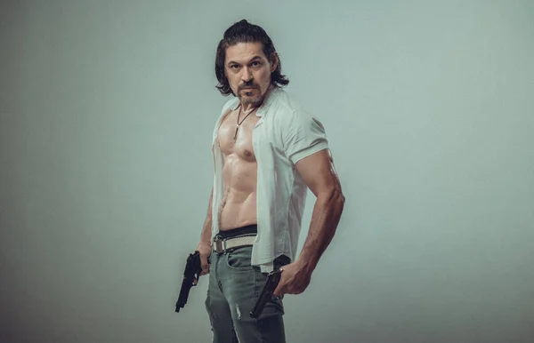 Sexy muskulösen Körper Modell Porträt eines jungen Mannes mit einer Waffe in seinen Händen — Stockfoto