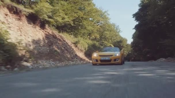 Желтый автомобиль на лесной дороге — стоковое видео