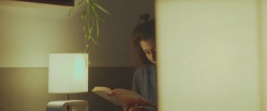 Geceleri rahat bir kafede oturup kitap okuyan güzel bir kız.