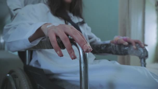 Női nővér tolta a beteget a tolószékbe a kórházi folyosón keresztül. — Stock videók