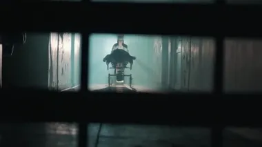 Kadın hemşire hastayı hastane koridorunda tekerlekli sandalyeye oturtuyor.