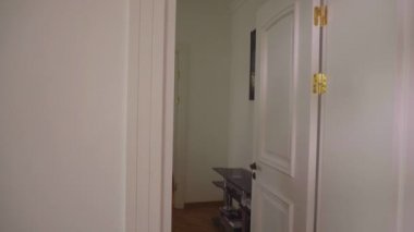 Yalnız bir adam evdeki koridorda yürüyor.