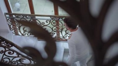 Üzgün adam evin merdivenlerini çıkıyor.