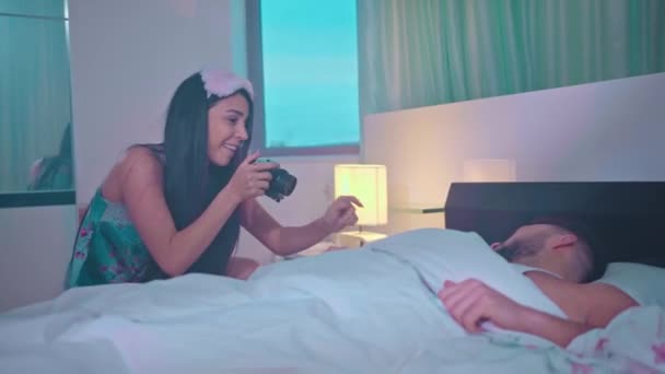 Девушка проснулась спящий парень утром в спальне делает фото Красивая любящая пара целуется в постели — стоковое видео