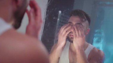 Mutsuz adam üzgün bir şekilde aynaya bakar.