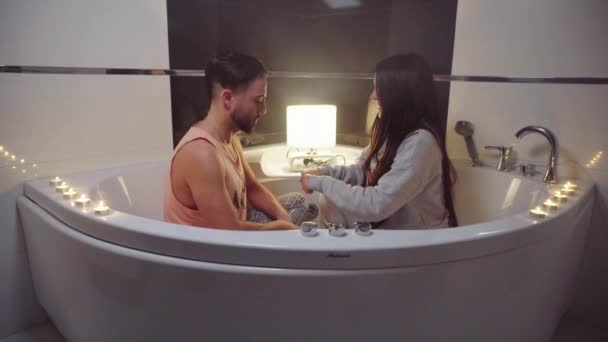 Couple in love jokes and laughs tenderly caressing each other while sitting in the bathroom — Stock Video