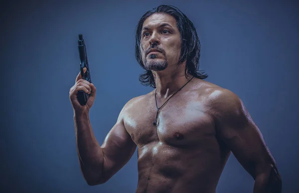Elinde silah tutan genç bir adamın kaslı vücut modeli portresi..