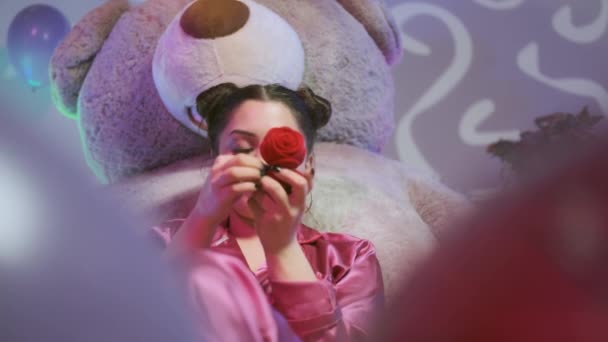 Счастливая девушка в розовом пиджаке играет с кольцом, смотрит в камеру и становится счастливой — стоковое видео