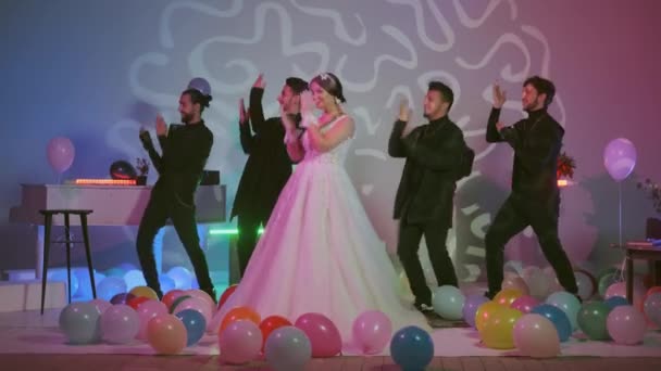 Schönheit Braut in Brautschleier und Gäste tanzen in Hochzeit .Schöne Modell Mädchen in einem weißen Brautkleid, bunte Luftballons auf dem Boden, Zimmer mit mit bunten Neonlichtern dekoriert — Stockvideo