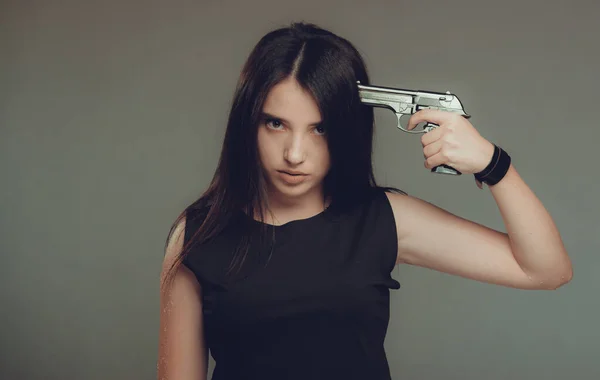 Young woman at despair holding a gun to her head,