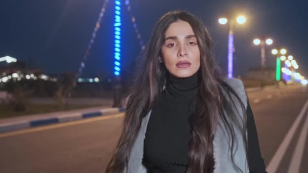Chica joven caminando por la calle iluminada de la ciudad por la noche — Vídeos de Stock