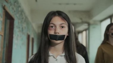 Hüzünlü, depresyondaki liseli kız zorbalığın kurbanı, ağzı siyah bantla kaplı.