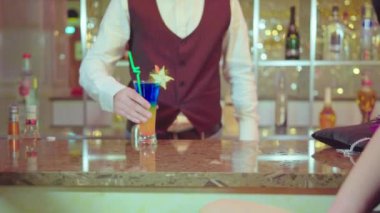 Barmen müşteriye kokteyl verir.