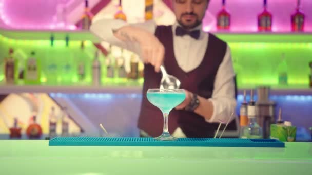Der Barkeeper drückt eine Zitrone in ein Glas mit einem Cocktail. — Stockvideo