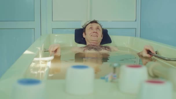 L'homme est couché dans la salle de bains. procédure thérapeutique c bain, relaxation et récupération. traitements de l'eau pour l'homme — Video