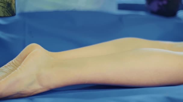 Entspannte junge Frau liegt auf einem Wellnessbett zur Körpermassage mit Schlamm und Gewürzen durch einen Masseur in einem luxuriösen Wellness-Resort, Peeling-Peeling-Schönheitsbehandlung — Stockvideo