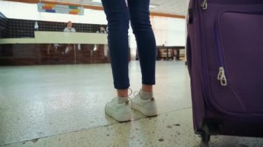 Elinde büyük bir bavul olan bir kadın otel lobisinde eşyalarını sürüklüyor, kadın bir bavul taşıyor.