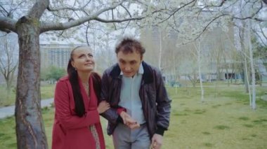 Orta yaşlı bir çift parkta bir ağaca yaklaşır ve konuşur.