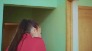 Orta yaşlı kadın odaya bakar, hoşuna gider, güler ve sevinir.