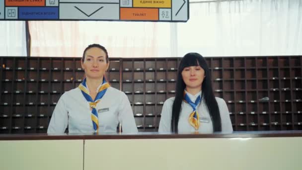 Two beautiful young stylish receptionists at a reception desk, welcome guests — Stock Video