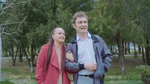 公園を歩いている中年のカップル、女性は赤い服を着ています — ストック動画