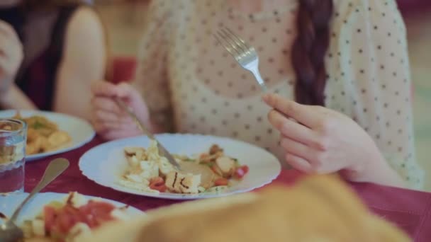 Movimiento de la cámara de la placa con carne a la cara de las mujeres. Primer plano de una mujer joven que usa tenedor para tomar carne frita de su plato. Almuerzo en la cafetería — Vídeo de stock