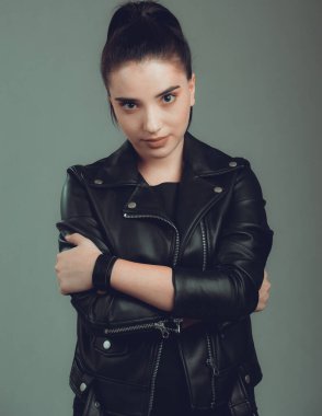 Gri arka planda siyah deri ceketli güzel bir kadının portresi.