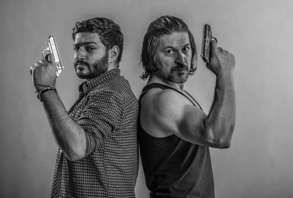 Silahlar iki gangsterin elinde, kızgın kameraya bakıyorlar, siyah tişört giymiş, mafya tarafından kutsanmış.,