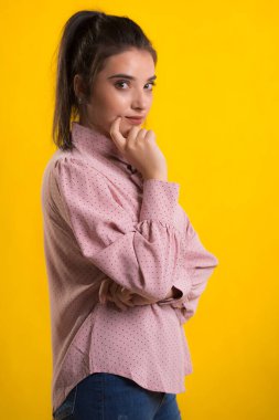 Pembe süveter giyen genç, güzel esmer model, arkasında mavi arka plan, okşama çok tatlı görünüyor, stüdyoda poz veriyor.,