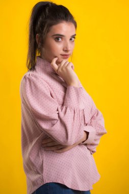 Pembe süveter giyen genç, güzel esmer model, arkasında mavi arka plan, okşama çok tatlı görünüyor, stüdyoda poz veriyor.,