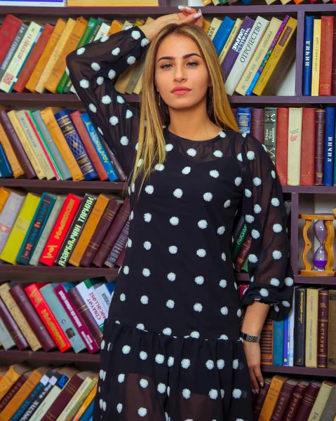 Çekici genç sarışın model, model kadın kitaplığın önünde duruyor.,