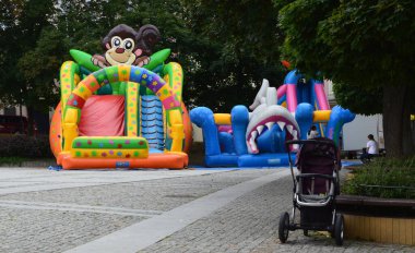 Bir kaldırım taşı eğlence parkında çocukların trambolinleri ve boş bir bebek arabası.