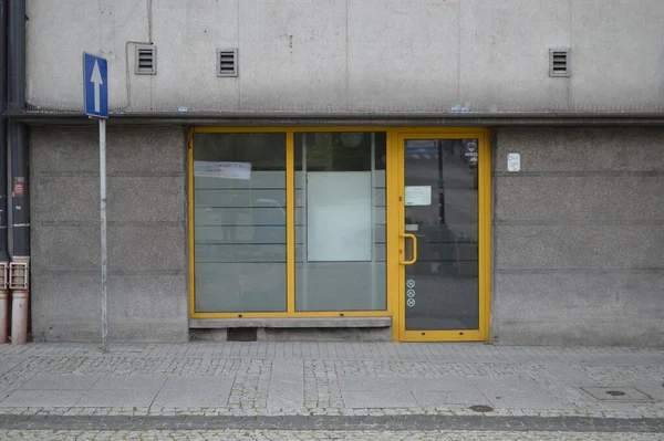 Yellow glass plastic doors in a gray building and blue road sign