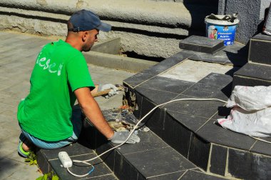 Adam yerdeki fayansları onarıyor. Ukrayna, Kiev, 13.06.2019.