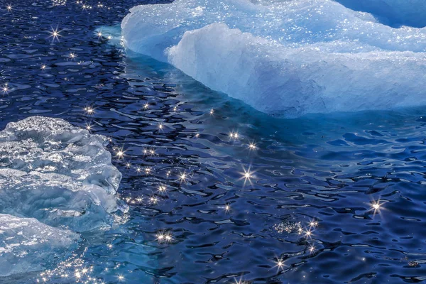 Des morceaux dérivants d'iceberg bleu et de soleil scintillant sur l'eau — Photo