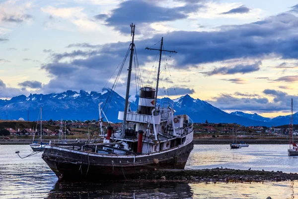 Starý nefunkční lodi uvízlých na pobřeží a vesnice s horami v th — Stock fotografie