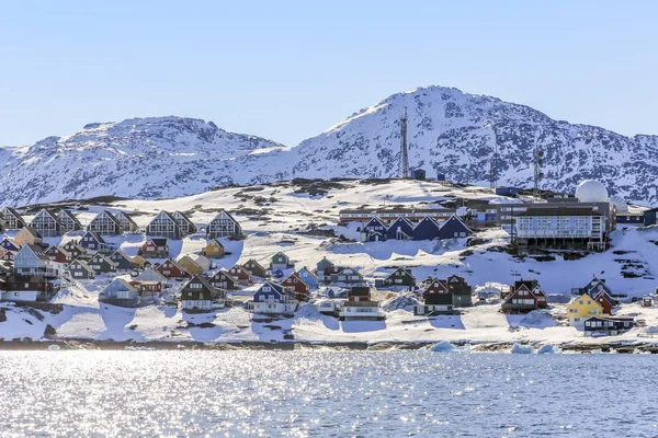 Rader av färgstarka Inuit hus längs fjorden med snö berg — Stockfoto