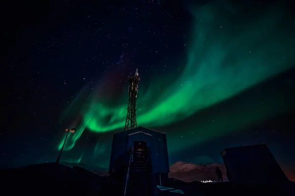 Grüne Wellen von Polarlichtern mit leuchtenden Sternen über dem Berg — Stockfoto