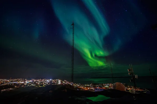 Зеленые волны Aurora Borealis с сияющими звездами над фьордом — стоковое фото